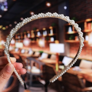 Close-up of white pearls on a gold metal headband with a blurred cafe background