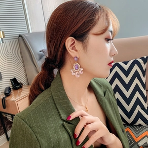 Detail of long drop earrings featuring purple and pink crystal stones worn by a model