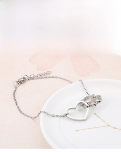 Detail of silver heart and miniature knuckle duster charms on a stainless steel bracelet