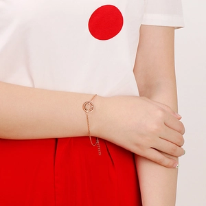 Minimalist 18K rose gold smile emoji charm bracelet worn on a woman's wrist