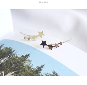 Close-up of S925 silver star ear crawlers in gold and silver finish on artistic background