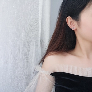 Detailed view of silver S925 star earrings worn along the curve of the earlobe