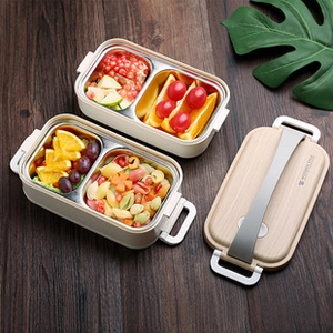Close-up of double-layer stainless steel bento box with wood grain lid and compartments