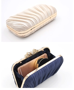 Detail of satin pleated evening clutch with golden bow clasp and interior storage capacity