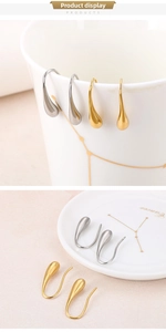 Detailed view of teardrop earrings in gold and silver hanging on a white ceramic cup
