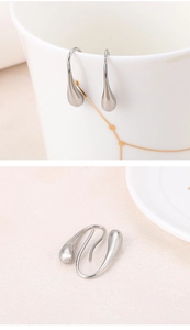 Detailed macro view of silver teardrop stainless steel earrings on a ceramic cup and surface