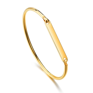 Detailed view of polished gold metal C-shape cuff bracelet with engraving plate