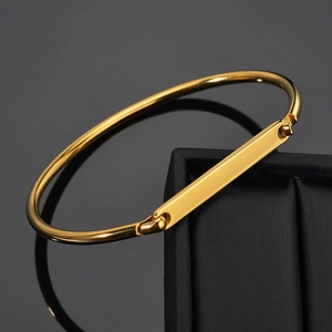 Detailed view of polished gold plated cuff bracelet with custom engraved rectangle plate