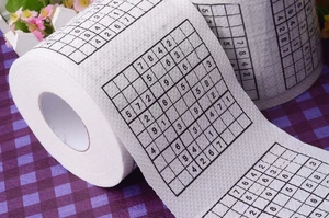 Macro detail of soft white toilet paper roll featuring printed Sudoku game puzzle design