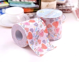 Close-up of printed toilet paper with colorful heart patterns and sweet text in a gift box
