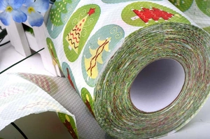 Detail shot of toilet paper roll featuring colorful Christmas tree prints on white paper