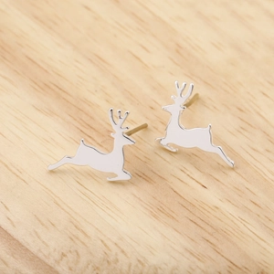 Detailed close-up of jumping reindeer stud earrings on a natural wood surface