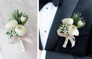 Detail of beige rose boutonniere with gold-striped ribbon on wedding dress and black suit