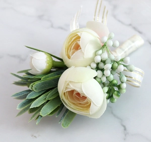 Detail of cream artificial ranunculus boutonniere with green leaves and ribbon decoration