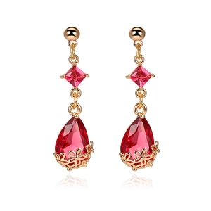 Detail view of 18K gold teardrop earrings featuring faceted red crystal and floral filigree