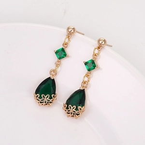 Detailed macro view of vintage gold teardrop earrings with green crystal gemstones