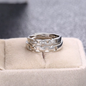 Macro shot of silver chain design couple rings with zircon inlays in a beige velvet box