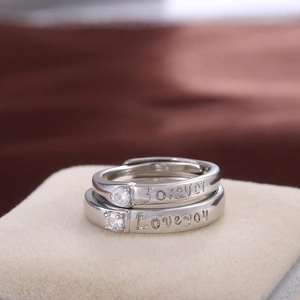 Macro shot of silver couple rings with Forever Love You engraving and sparkling zircons