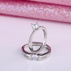 Close-up of silver-plated couple rings with sparkling stones on pink sparkling background