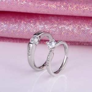 Macro view of silver adjustable couple rings with cubic zirconia on pink background
