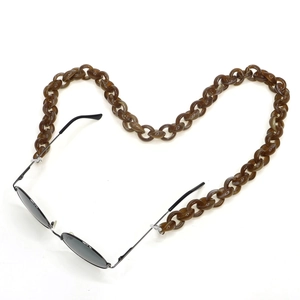 Brown tortoise acrylic eyeglass chain in heart shape with sunglasses on white base