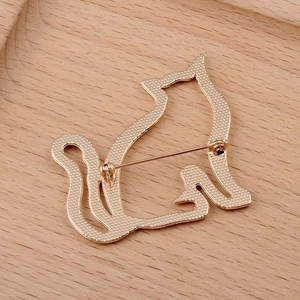 Macro detail of golden cat brooch back showing grid texture and pin clasp on wood