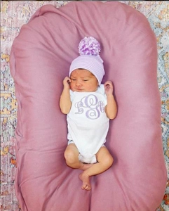 Detail of baby striped knitted hat with fluffy pompom and comfortable earmuff design