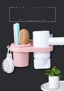 Detail view of pink wall-mounted hair dryer holder with comb storage and utility hooks