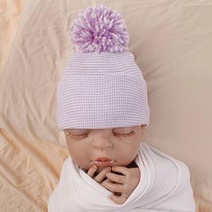 Detail view of double-layer striped newborn knit hat with a fluffy pom-pom on top