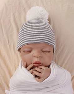 Detail view of double-layered striped newborn baby knit hat with white pom-pom decoration