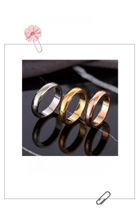Three minimalist titanium steel rings in silver, gold and rose gold colors on black surface