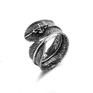 Detalle macro de un anillo de pluma en plata antigua con cruz central y diseño abierto