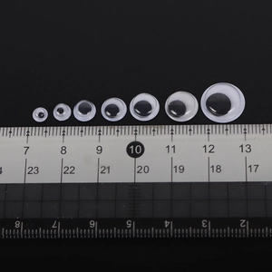 Various sizes of plastic googly eyes measured on a ruler from 4mm to 20mm with a black background
