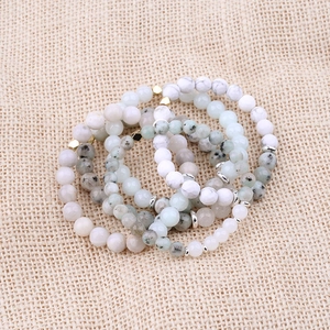 Natural moonstone beaded bracelet stack with gold stars on a rustic woven background