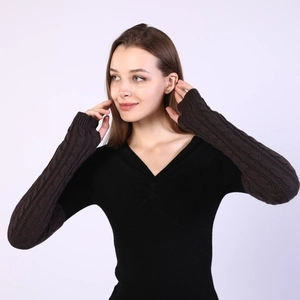 Detail of dark brown cable-knit arm warmers showing thick wool texture and wrist fit