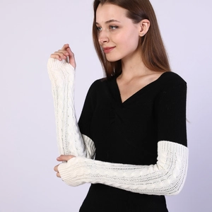 Close-up of cream cable-knit arm warmers with thumb holes and textured wool blend