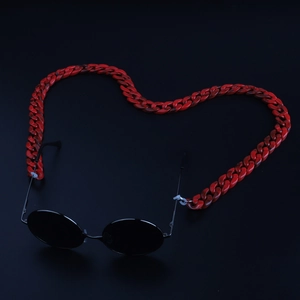 Macro detail of red and black acrylic leopard link chain attached to sunglasses