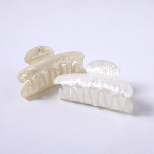 Detail of marble pattern and pearl white acetate hair claws for elegant hairstyling