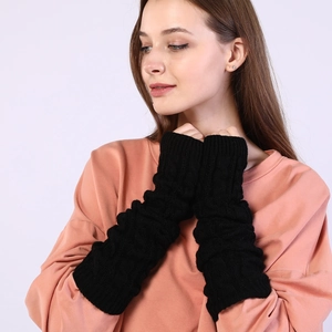 Detail of black knit arm warmers showing thick cable knit texture and fingerless design