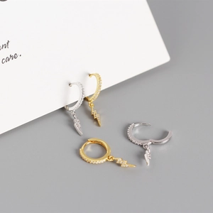 Detailed macro view of lightning bolt earrings in gold and silver finish with zircon inlays