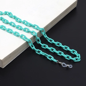 Detailed close-up of teal acrylic glasses chain with metal clips and rubber loops on a book