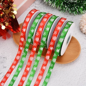 Red and green Christmas ribbons with snowflake patterns on a rustic wooden tray