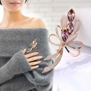 Spilla a fiocco in oro rosa con cristalli viola e piccoli diamanti su un maglione grigio