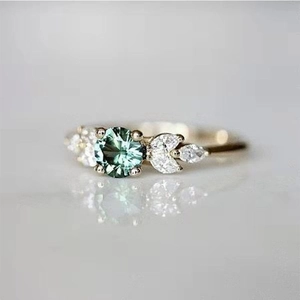 Macro detail of vintage gold ring with round emerald center and marquise side diamonds