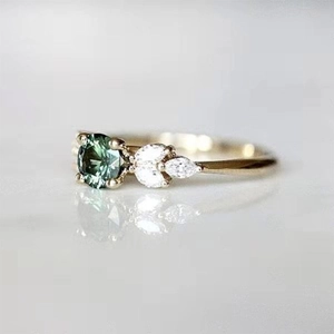 Macro side view of emerald ring with gold band and leaf-shaped diamond accents