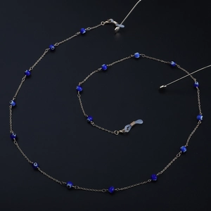 Catenella per occhiali dorata con perline blu Evil Eye e gommini su superficie nera