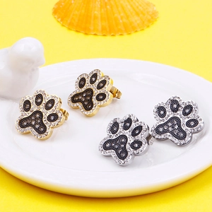 Cute gold and silver pavé crystal paw print stud earrings on a white ceramic plate