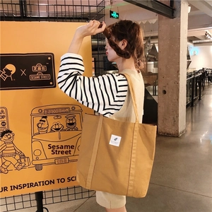 Close-up of brown canvas tote bag with wide shoulder strap and spacious bottom design