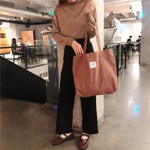 Brown corduroy tote bag detail showing large capacity and label on model's shoulder