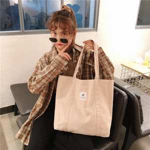 Lifestyle view of a minimalist cream canvas tote bag with a small botanical patch detail
